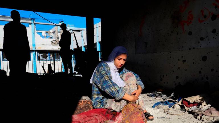 Hala Al-Masri, 17, sits at the site of an overnight Israeli strike on an UNRWA school that was sheltering displaced people, in Khan Younis, southern Gaza Strip, August 3, 2025. REUTERS/Hatem Khaled TPX IMAGES OF THE DAY