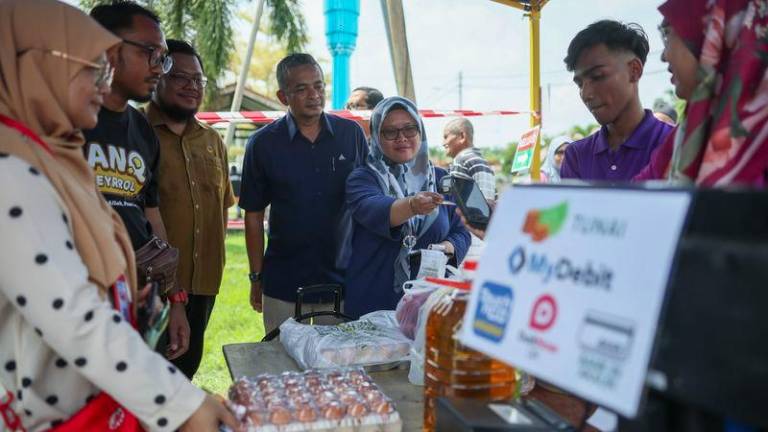 Pengarah Suruhanjaya Komunikasi dan Multimedia (MCMC) Negeri Pahang, Shahrizal Husin (empat dari kiri) melihat pengguna membuat pembayaran menggunakan kad debit pada Pelancaran Program Cashless @ NADI Jenderak Utara di Felde Jenderak Utara hari ini. - fotoBERNAMA