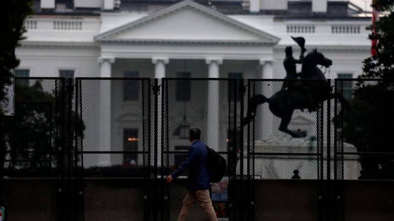 A man walks next to the anti-climb fence placed near the White House, in Washington, D.C. U.S., September 24, 2025. REUTERS/Daniel Becerril