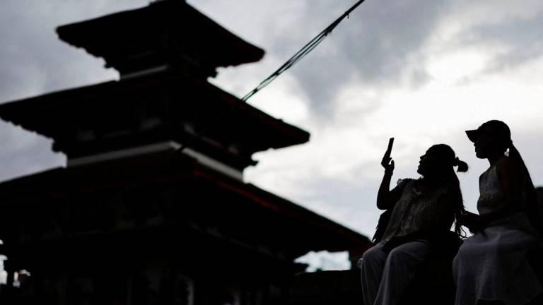 A woman uses her phone at Bashantapur Durbar Square after the government announced it will close all social media not registered with the government saying the move was aimed at managing and making the social media responsible, in Kathmandu, Nepal September 4, 2025. REUTERS/Navesh Chitrakar