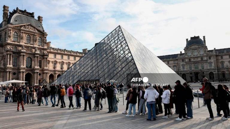Visitors queue in front of the Pyramide du Louvre, designed by Chinese-US architect Ieoh Ming Pei, with the Louvre Museum in the background in Paris on October 22, 2025. - Thibaud MORITZ / AFP