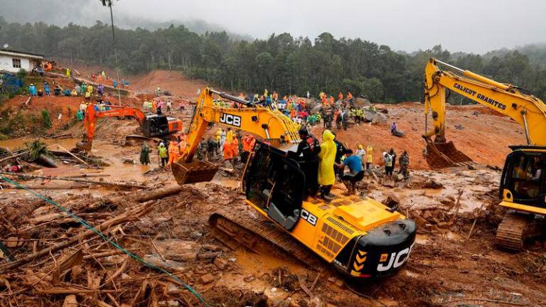 People stand as search operations are carried out after landslides hit Mundakkai village in Wayanad district in the southern state of Kerala - REUTERSpix