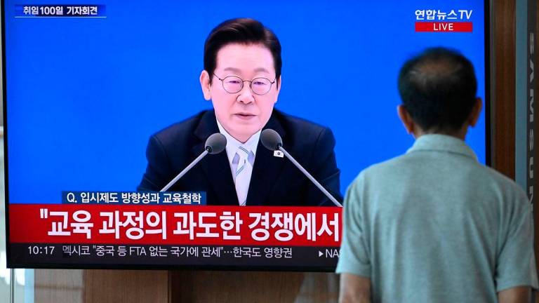 A man watches a television screen showing a live broadcast of South Korean President Lee Jae Myung speaking during a press conference to mark his first 100 days in office, at a train station in Seoul on September 11, 2025. (Photo by Jung Yeon-je / AFP)