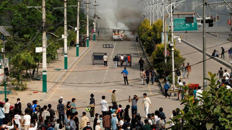 Smoke billows from an ambulance next to riot police officers and demonstrators during a protest against corruption and the government’s decision to block several social media platforms, in Kathmandu, Nepal September 8, 2025. REUTERS/Stringer