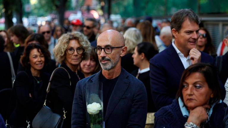 A man holding a rose looks on while people queue outside the Armani/Teatro to pay tribute to designer Giorgio Armani, following his death at the age of 91, in Milan, Italy September 6, 2025. - REUTERS