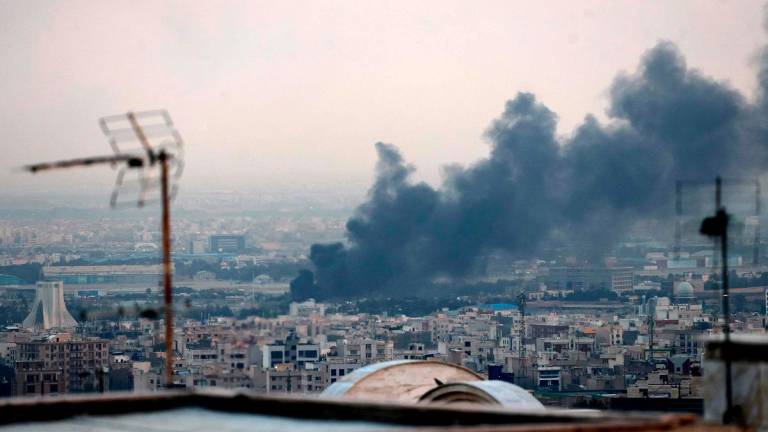 Smoke billows from an explosion near the Azadi Tower (L) in Tehran on June 16, 2025. The Islamic Republic of Iran Broadcasting (IRIB) building was struck in an Israeli attack on June 16, cutting live coverage immediately. The blast occurred as the presenter was live on TV lambasting Israel before she was seen leaving the live broadcast, Iranian media reported, sharing a video of the incident. - ATTA KENARE / AFP
