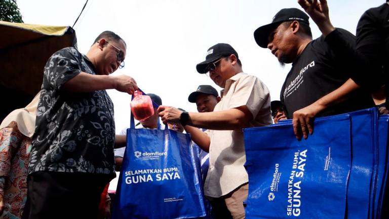 Yang Dipertua Majlis Perbandaran Temerloh, Rizal Mustafa (dua, kanan) bersama Ketua Pegawai Operasi Alam Flora Mohamad Muhazni Mukhtar (kanan) mengagihkan beg guna semula secara percuma kepada pengunjung pada program Kempen Bawa Beg Guna Semula di Pekan Sehari hari ini - BERNAMA