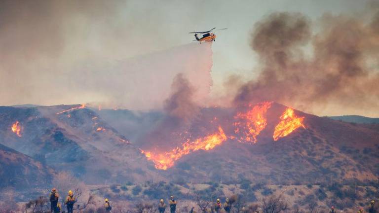 A helicopter drops water as the Hughes Fire burns in Castaic Lake, California - REUTERSpix