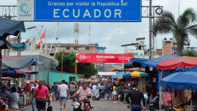 People walk and ride in Huaquillas, Southern Ecuador, on the border with Peru on February 8, 2025, on the eve of the presidential election. - AFPPIX