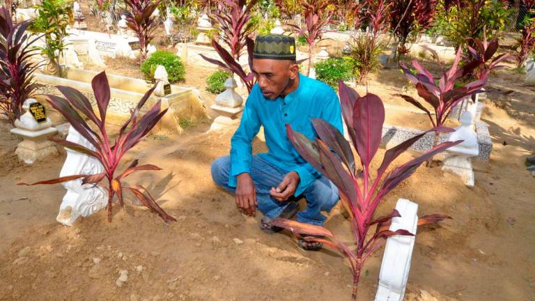 Fadli Abdul Rahman, 50, father of the late Fatin Nasrien, 22, recites a prayer at his daughter’s grave, who died in the tragedy near Tasik Banding last Monday, at the Kampung Kerandang Islamic Cemetery today. - BERNAMAPIC