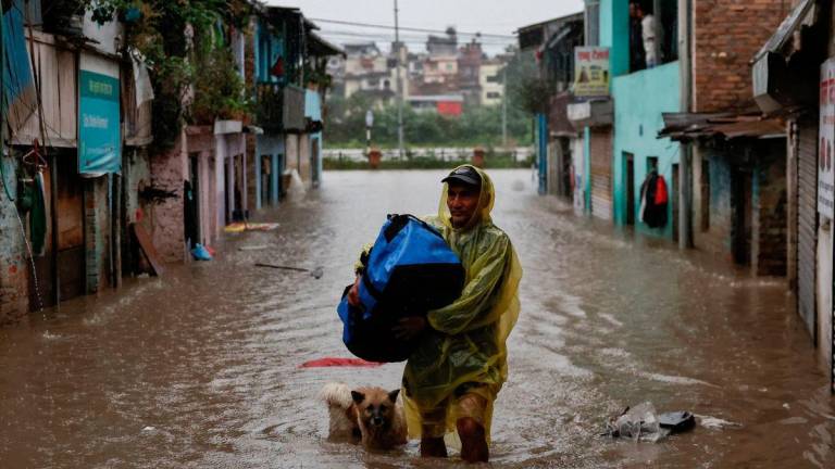 A man carries a bag as he wades through a flooded street along the bank of overflowing Bagmati River following heavy rains, in Kathmandu, Nepal, October 4, 2025. REUTERS/Navesh Chitrakar