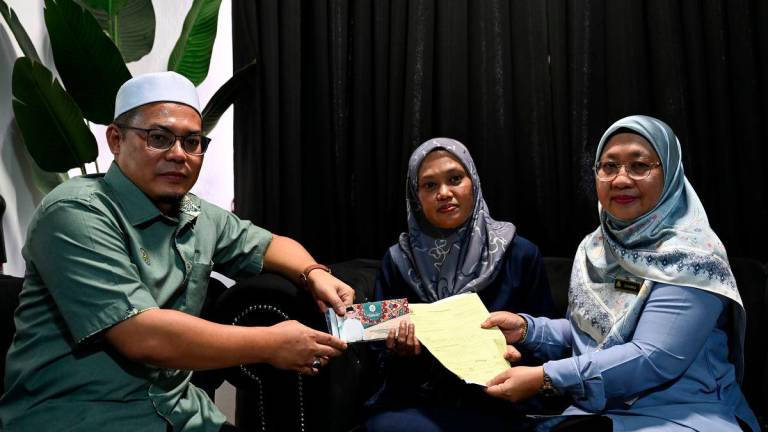 Pengerusi Jawatankuasa Pembangunan Belia, Sukan dan Badan Bukan Kerajaan Negeri, Hishamuddin Abdul Karim (kiri), bersama Pengarah Pertubuhan Keselamatan Sosial (PERKESO) Terengganu, Suhara Mustaffa (kanan), menyampaikan faedah kepada Rusmailaili Samsuri, 43, (tengah), ibu kepada atlet angkat berat Sukan Malaysia (SUKMA) Terengganu, Allahyarham Siti Noralyaa Mat Marzuki, pada Majlis Penyampaian Faedah Pengurusan Mayat (FPM) di Taman Batin Perdana hari ini. - fotoBERNAMA