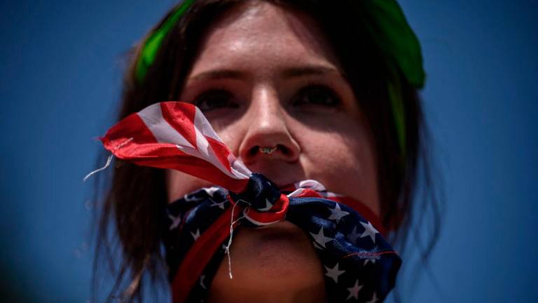 A reproductive rights activist, gagged by a scarf in the colors of the US flag, marches during a protest against a recent Supreme Court ruling on abortion rights, in New York, July 4, 2022. (Photo by Ed JONES / AFP)