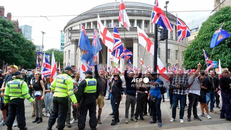 Far-right Britain First party supporters wave Union Flags and St George Cross flags during an anti-immigration 'March for Remigration' calling for mass deportations, in Manchester, northwest England, on August 2, 2025. - PETER POWELL / AFP