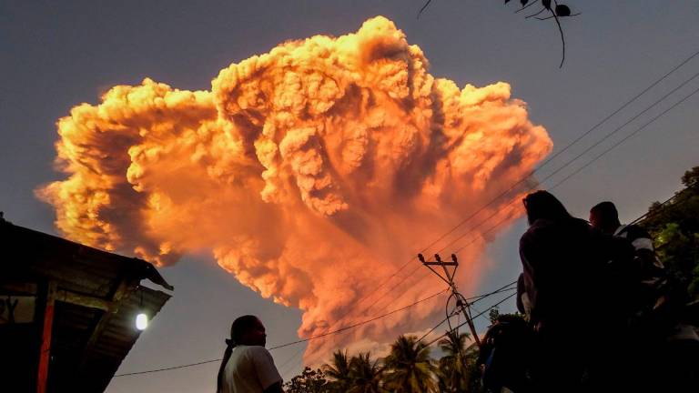 Villagers watch the eruption of Mount Lewotobi Laki-Laki as seen from Talibura village in Sikka, East Nusa Tenggara, on June 17, 2025. A volcano in eastern Indonesia spewed a colossal ash tower into the sky on June 17, authorities said, after they raised its alert level to the highest of a four-tiered system. - AFP
