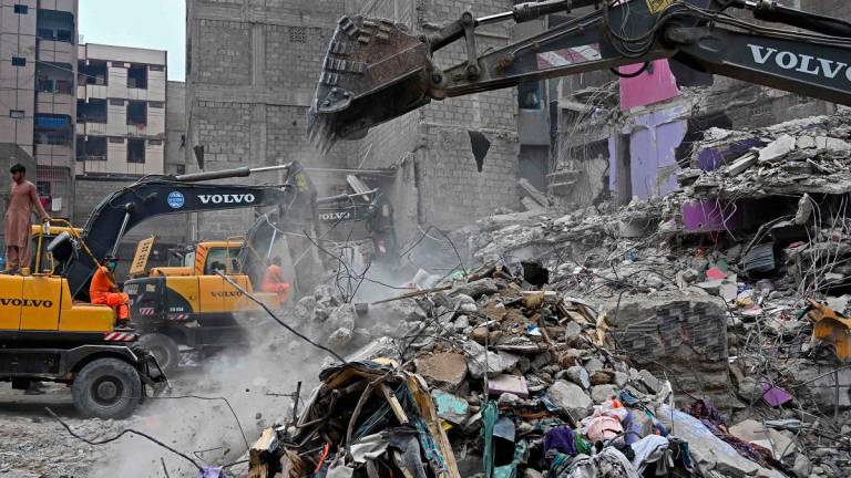 Rescue workers conduct a search operation amid the debris of a collapsed residential building in Karachi on July 5, 2025. Rescue teams pulled more bodies from the rubble of a five-storey building collapse in Pakistan overnight, taking the toll on July 5 to 14 as the recovery operation continued for a second day. - Rizwan TABASSUM / AFP
