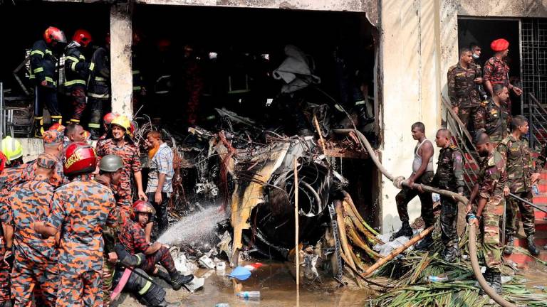 Firefighters and army members work next to the wreckage of an air force training aircraft after it crashed into Milestone College campus, in Dhaka, Bangladesh, July 21, 2025. - REUTERS/Stringer
