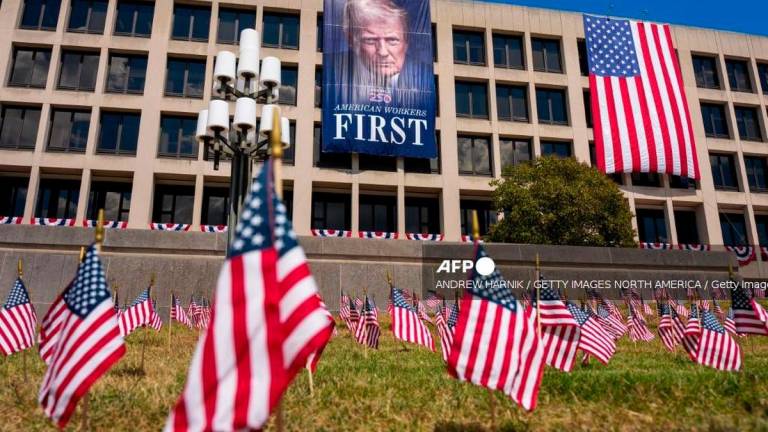 Hundreds of small American flags stick out of the lawn and a photo of U.S. President Donald Trump is displayed on the side of the U.S. Department of Labor on August 29, 2025 in Washington, DC. The Trump administration has deployed federal officers and the National Guard to the District in order to place the DC Metropolitan Police Department under federal control and assist in crime prevention in the nation’s capital. Andrew Harnik/Getty Images/AFP (Photo by Andrew Harnik / GETTY IMAGES NORTH AMERICA / Getty Images via AFP)