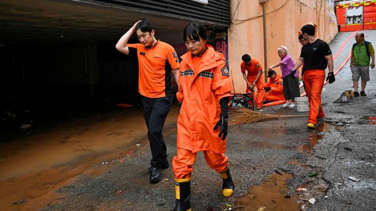 Rescue members pump out water from a parking lot after flooding caused by record-breaking rains in Seosan on July 17, 2025. Parts of South Korea were battered by torrential rains July 17, with one region pummelled by the most rainfall per hour since full records began in 1904, the country’s weather agency said. - Jung Yeon-je / AFP