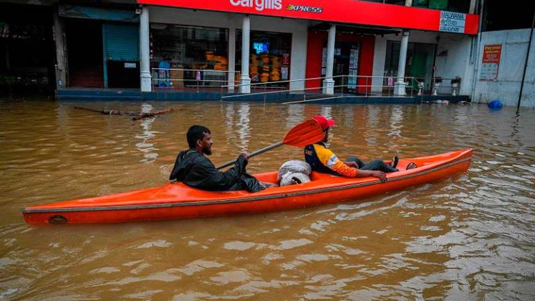 A resident rows a boat through a flooded street after heavy rains in Malwana on the outskirts of Colombo on June 2, 2024. Flash floods, mudslides and falling trees have killed at least 14 people in Sri Lanka as the island nation is battered by monsoon storms, the country’s disaster centre said on June 2. - Ishara S.Kodikara / AFP