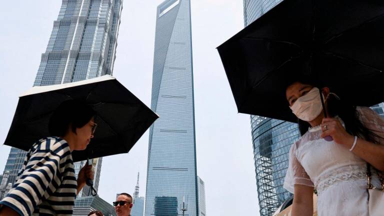 People walk near Shanghai World Financial Center, where a Wells Fargo office is situated, in the Lujiazui financial district in Shanghai, China, July 18, 2025. - REUTERS/Go Nakamura/File Photo