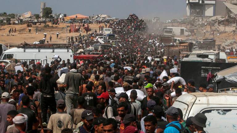 Displaced Palestinians carry food parcels as they raid trucks carrying humanitarian aid in Khan Yunis, in the southern Gaza Strip on August 9, 2025. Nearly two years into the war in Gaza, Israel’s Prime Minister Benjamin Netanyahu faces mounting pressure to secure a truce to pull the territory’s more than two million people back from the brink of famine and free the hostages held by Palestinian militants. - AFPpix