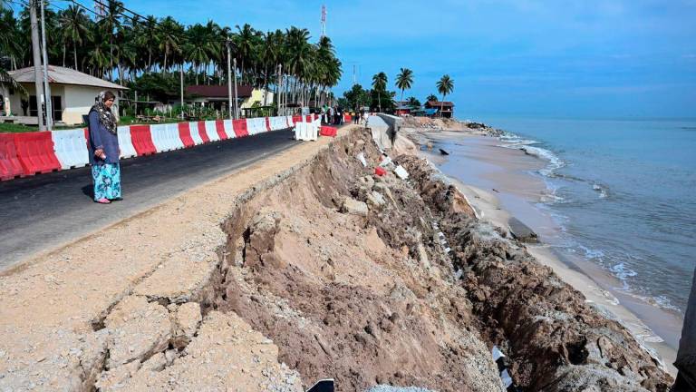 A resident, Maimun Johar, 56, surveys the aftermath of a collapsed embankment structure near her home, which sustained severe damage believed to have been caused by coastal erosion last night, during an inspection at Kampung Tanjung today. – BERNAMA