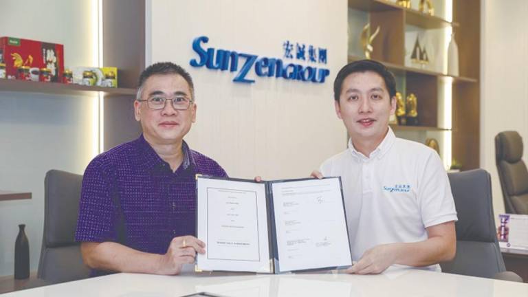 Lee (left) and Teo displaying the share sale agreement.