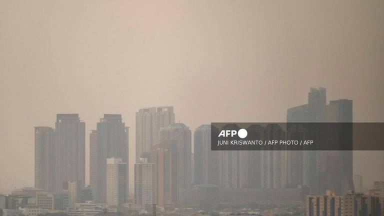 Skyscrapers are seen shrouded by polluted air in Jakarta on October 23, 2024. - JUNI KRISWANTO / AFP