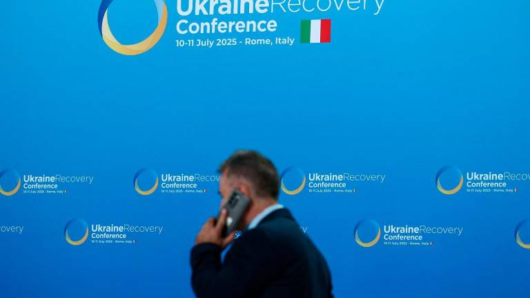 A person holds a phone while walking, on the first of the two-day Ukraine Recovery Conference (URC2025), on plans for the reconstruction of Ukraine, in Rome, Italy, July 10, 2025. - REUTERS/Guglielmo Mangiapane