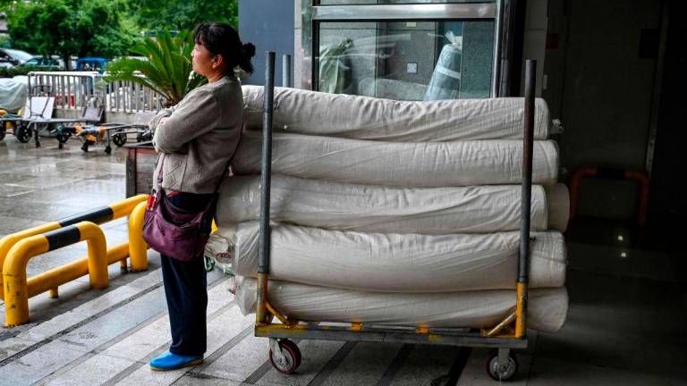 A woman waits with rolls of fabric at an entrance of the Keqiao China Textile City, one of the biggest textile markets in Asia, in Shaoxing in China’s eastern Zhejiang province on May 8, 2025. AFPpix