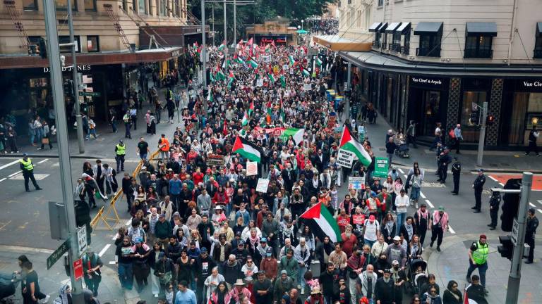 Demonstrators hold placards and flags as they take part in the ‘Nationwide March for Palestine’ protest in Sydney, Australia, August 24, 2025. Picture taken through glass. REUTERS/Hollie Adams