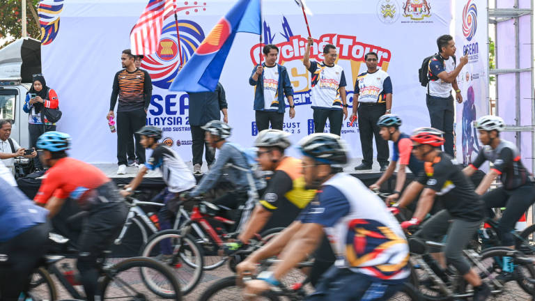 Deputy Minister of Youth and Sports, Adam Adli Abdul Halim (centre), performs the symbolic flag-off of participants of the ASEAN Solidarity Cycling Tour at Dataran Pantai Batu Buruk today. – BERNAMA