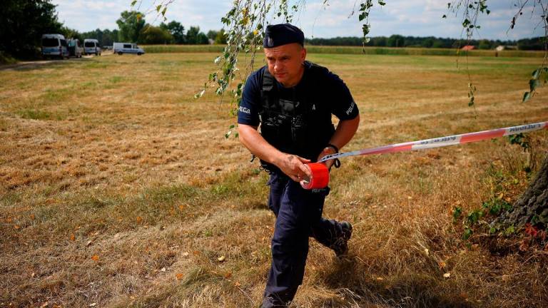 A police officer sets up a police tape, after an unidentified object fell and exploded in a cornfield overnight, according to Polish authorities, in the village of Osiny, eastern Poland, August 20, 2025. - REUTERS/Kacper Pempel