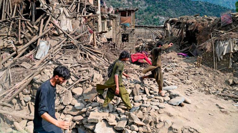 Afghans walk past damaged houses, after earthquakes at Mazar Dara village in Nurgal district, Kunar province, in Eastern Afghanistan, on September 1, 2025. - AFPPIX