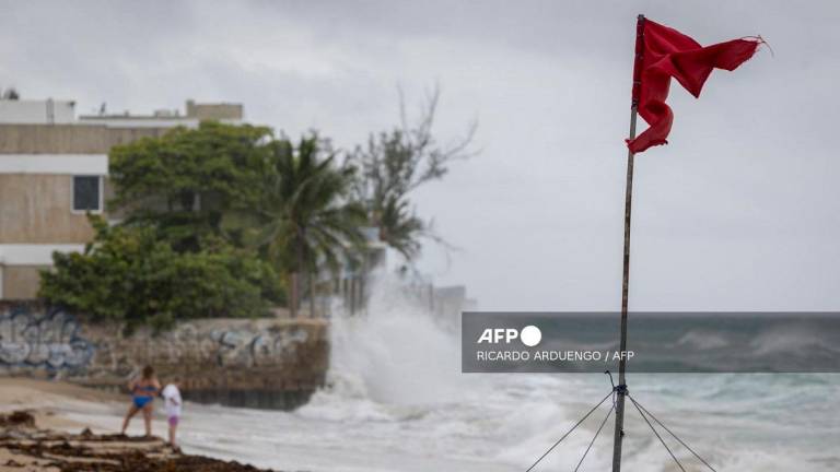 A ripped red flag warning of rip current waves as Category 5 Hurricane Erin approaches in San Juan, Puerto Rico, on August 16, 2025. Hurricane Erin on Saturday strengthened to a catastrophic Category 5 storm as it barrelled towards the Caribbean, with weather officials warning of possible flash floods and landslides. - Ricardo ARDUENGO / AFP