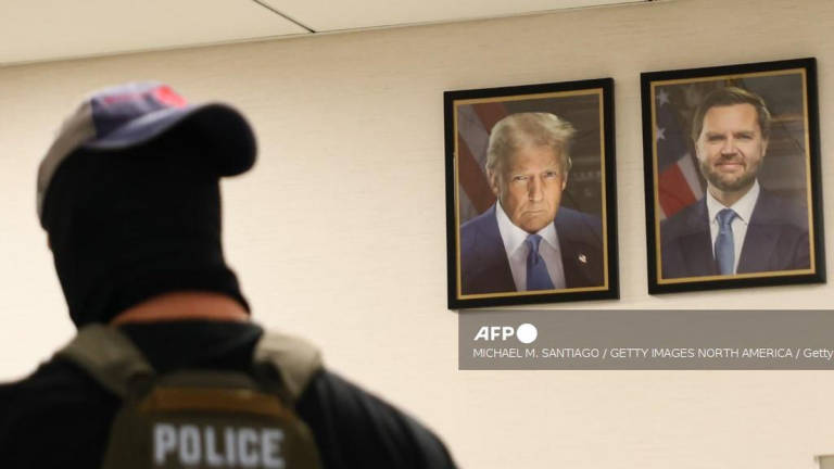 A federal agent walks past portraits of U.S. President Donald Trump and U.S. Vice President JD Vance as he patrols the halls of the Ted Weiss Federal Building on August 04, 2025 in New York City. - Getty Images via AFP