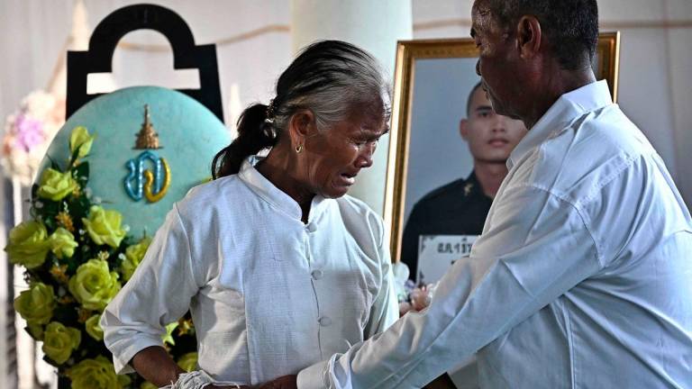 Kimdaeng Krajangthong (R) and Tin Krajangthong (C), the parents of Royal Thai Army soldier Theerayuth Krajangthong, 22, who died in clashes between Thailand and Cambodia in Sisaket province, mourn during funeral rites at a Buddhist temple in the Thai border province of Buriram on July 30, 2025. - Lillian SUWANRUMPHA / AFP