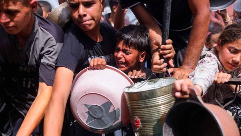Palestinians shove to get a portion of cooked food from a charity kitchen in Jabalia in the northern Gaza Strip on May 17, 2025. AFPpix
