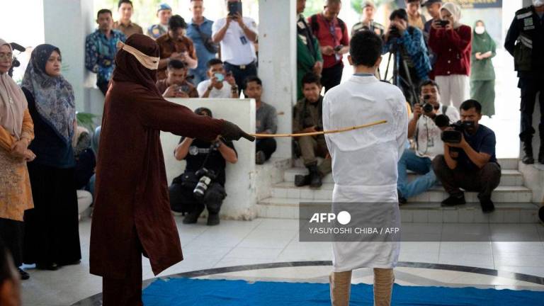 A man, found guilty of sexual relations with another man under the strict Islamic sharia law, is publicly flogged in Banda Aceh on February 27, 2025. (Photo by YASUYOSHI CHIBA / AFP)