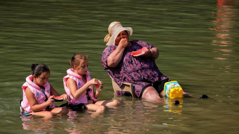 People cool off and eat watermelon in the Erenik River during the heat wave, near Gjakova, Kosovo June 25, 2025. REUTERS/Valdrin Xhemaj