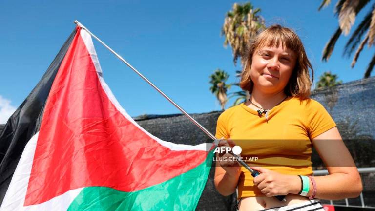 Swedish climate activist Greta Thunberg poses with a Palestinian flag as a flotilla carrying humanitarian aid and activists prepare to leave for Gaza, in Barcelona on August 30, 2025. (Photo by LLUIS GENE / AFP)