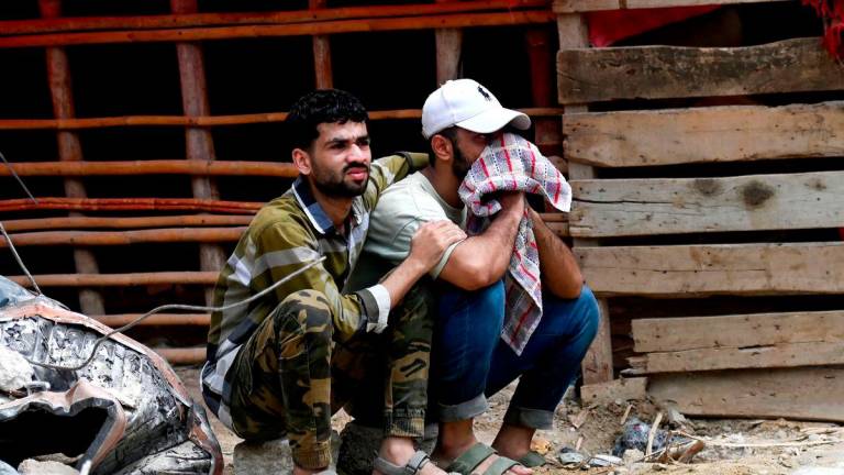 A victim waits with a relative, for recovery of his family members from the debris of collapsed building in Karachi on July 5, 2025. (Photo by Rizwan TABASSUM / AFP)