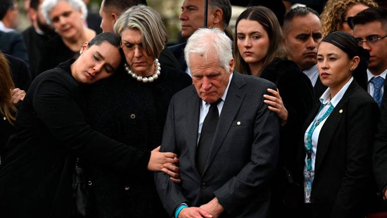 Miguel Uribe Londono (C), father of slain Colombian presidential candidate Miguel Uribe, looks at the coffin of his son during the burial at the Central Cemetery in Bogota on August 13, 2025. - Raul ARBOLEDA / AFP