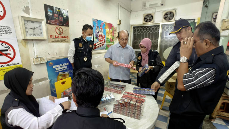 Melaka State Executive Councillor for Health, Human Resources, and Unity, Datuk Ngwe Hee Sem (fourth from right), and State Health Director, Dr Ruzita Mustaffa (third from right), inspect cigarettes believed to be counterfeit or smuggled, sold at prices below RM12, during the “Operasi Selamat Paru-Paru” late last night. – BERNAMA
