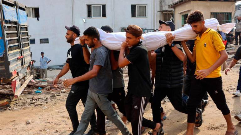 Palestinians carry the shrouded body of a loved one killed the previous day while seeking aid near Zikim, west of Beit Lahia, in the northern Gaza Strip, at Al-Shifa hospital in Gaza City on August 10, 2025- AFP