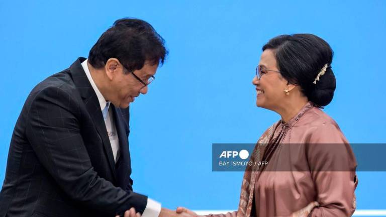 (FILES) Indonesia’s newly appointed Finance Minister Purbaya Yudhi Sadewa (L) and his predecessor Sri Mulyani Indrawati (R) shake hands after signing documents during the handover ceremony at the Ministry of Finance in Jakarta on September 9, 2025. In removing Indonesia’s finance minister and U-turning on protester demands, the leader of Southeast Asia’s biggest economy is scrambling to restore public trust while seizing a chance to install loyalists after deadly riots last month, experts say. (Photo by BAY ISMOYO / AFP)