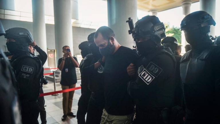 An Israeli man identified as Shalom Avitan (C) is escorted by Malaysian police upon his arrival at a court to face charges of possessing six handguns and 200 bullets in Kuala Lumpur on April 12, 2024. (Photo by Arif Kartono / AFP)