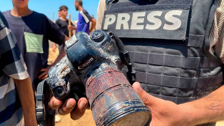 A journalist holds a blood-covered camera belonging to Palestinian photojournalist Hussam al-Masri, a Reuters contractor who was killed in an Israeli strike on Nasser hospital in Khan Yunis in the southern Gaza Strip, during his funeral on August 25, 2025. (Photo by AFP)
