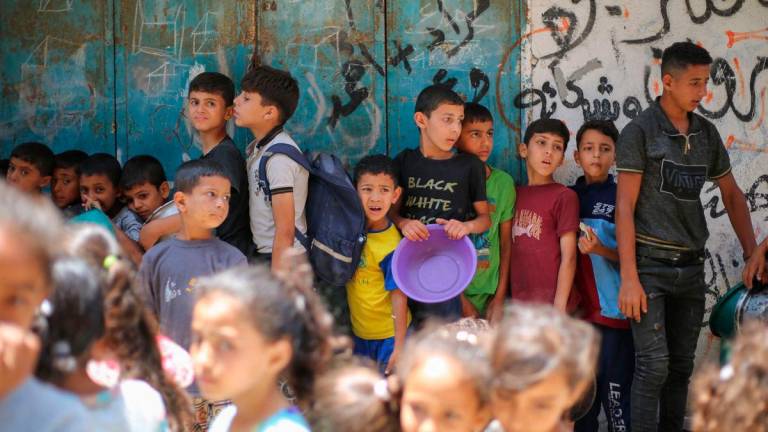 Palestinians queue at a food distribution point in Nuseirat, in the central Gaza Strip, on June 23, 2025. The Israeli blockade imposed in early March amid an impasse in truce negotiations had produced famine-like conditions across Gaza, according to rights groups. (Photo by Eyad BABA / AFP)
